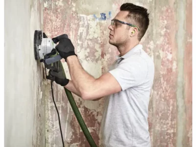 Festool Renofix RG 130 mit Absaugung beim Schleifen einer Wand.